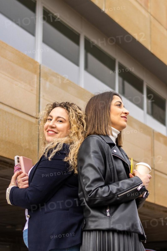 Portrait of two female entrepreneurs with crossed arms outside a building. Portrait of two business women outside a building