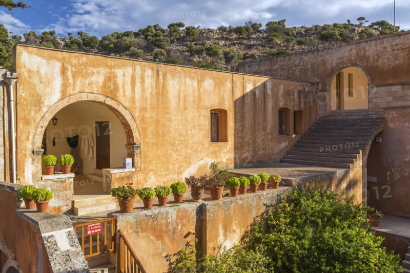 Stone staircase leading to cloister and wall with various plants in terracotta planters in inner courtyard at Holy Trinity (Agia Triada) Monastery, Akrotiri Peninsula, Chania region, Crete Island, Greece, Europe