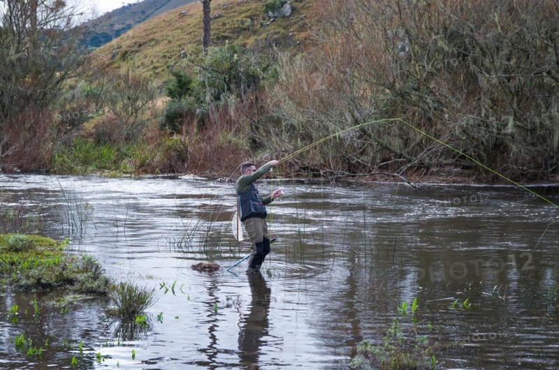 Fisherman fly fishing rainbow trout on mountain in beautiful scenery
