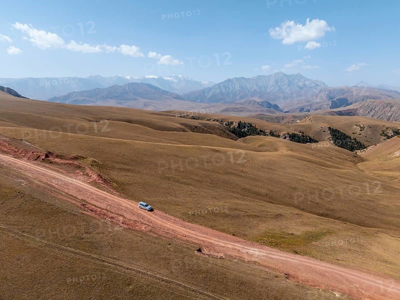 Moldo-Ashuu Pass, car on road between yellow hills, near Baetov, Naryn region, Kyrgyzstan, Asia