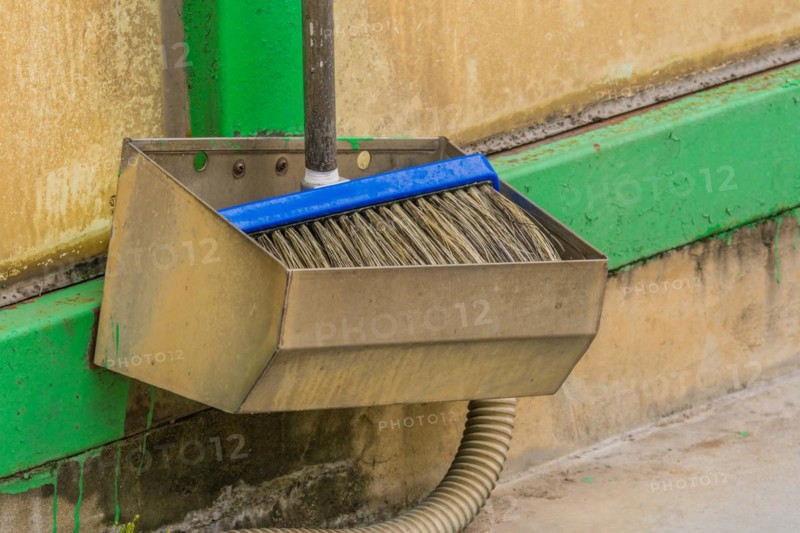 Car wash brush in metal holding trough mounted on green support beam in South Korea