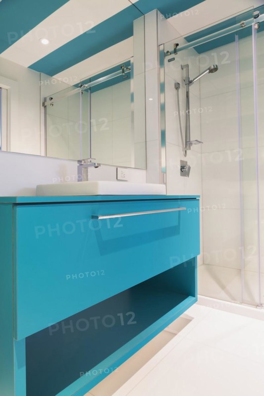 Blue laminated vanity with white rectangular shaped sink, clear glass shower stall in guest bathroom with white ceramic tile floor and blue and white striped ceiling inside contemporary home, Quebec, Canada, North America