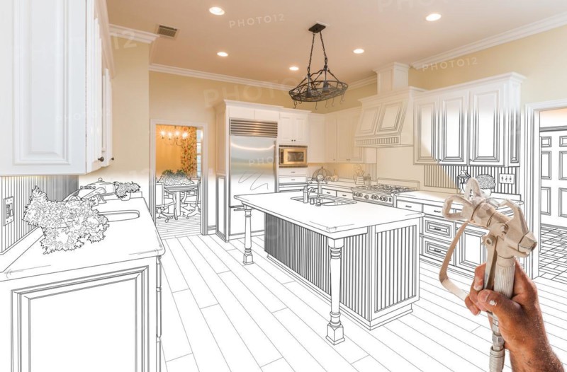 Professional spray painter holding spray gun spraying renovated kitchen over design drawing