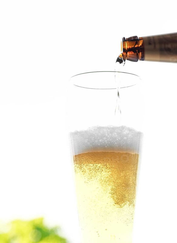 Beer is poured from a bottle into a glass, bubbles and foam are visible