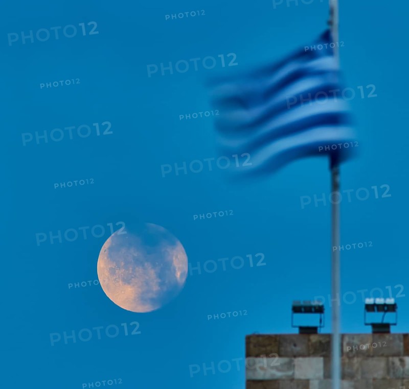 Full moon in semi-darkness next to a blurred flag at dusk, twilight, Mandraki harbour, Rhodes, Dodecanese, Greek Islands, Greece, Europe