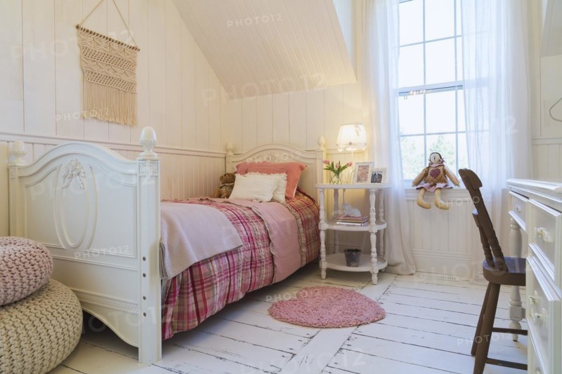 Single bed with red, pink and grey tartan bedspread, white painted antique style wooden headboard and footboard, nightstand, dresser with brown chair in a kid's bedroom with white painted larch wood floorboards on upstairs floor inside country style home, Quebec, Canada, North America