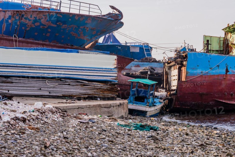 Old rusty abandoned ships sitting on the shore amid trash and debris at a marine junkyard in South Korea