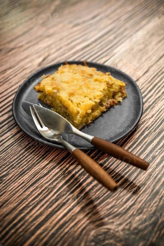 Plate with meat and grated potato pie on ceramic plate on rustic table