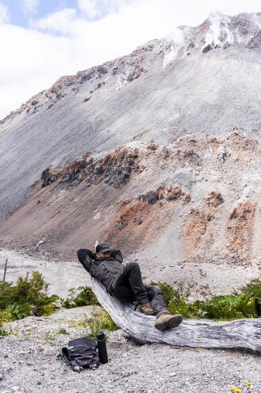 Young man relaxes in front of a volcano, Chaiten Volcano, Carretara Austral, Chile, South America