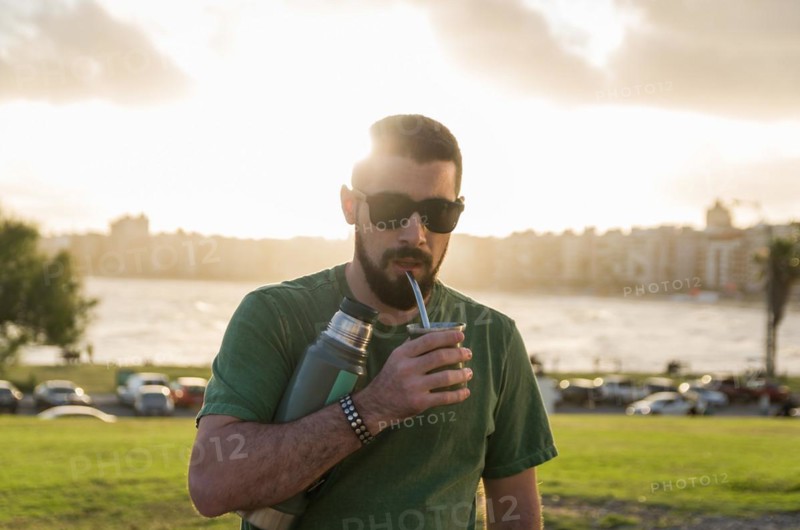 Man drinking chimarrao, mate tea tea (an infusion of yerba mate tea tea with hot water) at sunset in uruguay