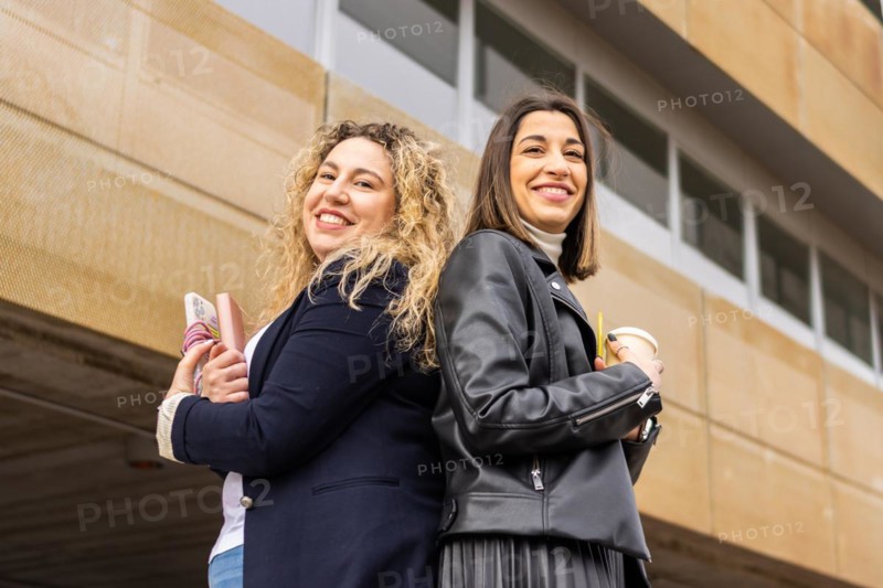 Portrait of two female entrepreneurs with crossed arms outside a building. Portrait of two business women outside a building