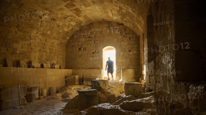 Knight's building, ground floor, A person stands in an illuminated stone tunnel that creates an interesting shadow play, St John's Fortress, Lindos, Rhodes, Dodecanese, Greek Islands, Greece, Europe