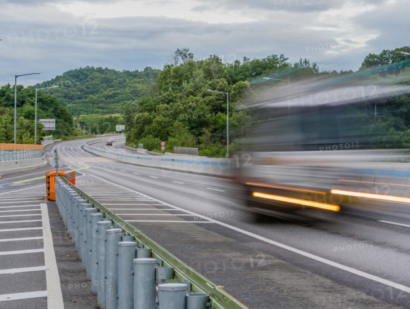 Streaks of light and blur of passing vehicle on highway in countryside location during blue hour under cloudy skies in South Korea
