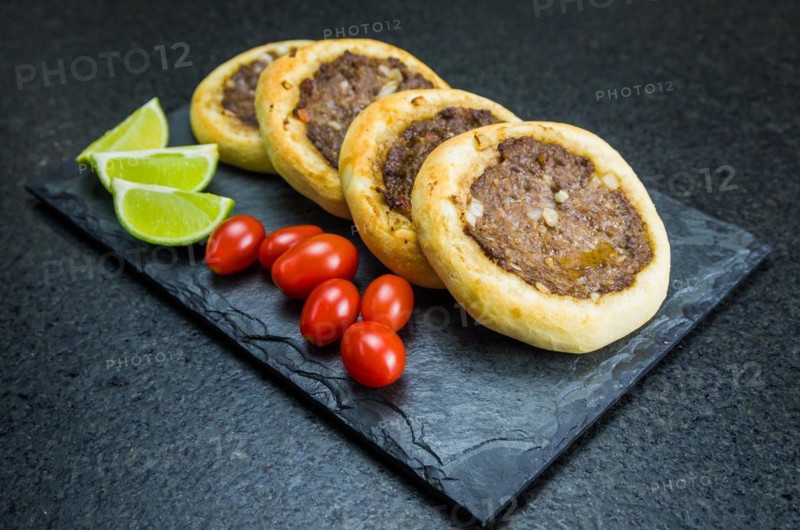 Delicious Lebanese (Arabic) food, genuine sfihas on a slate plate with tomatoes and lemons