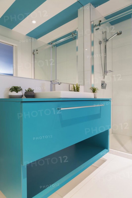 Blue laminated vanity with white rectangular shaped sink, clear glass shower stall in guest bathroom with white ceramic tile floor and blue and white striped ceiling inside contemporary home, Quebec, Canada, North America
