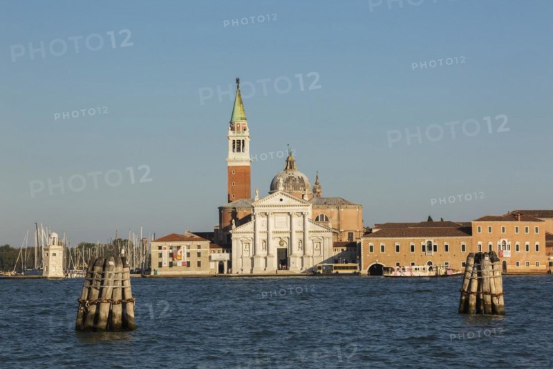 Canal lane markers in Venetian lagoon and 16th century Benedictine church of San Giorgio Maggiore on San Giorgio Maggiore Island, Venice, Veneto, Italy, Europe