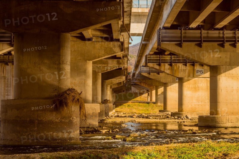 Underside view of columns of two highway overpass next to each other over river in South Korea