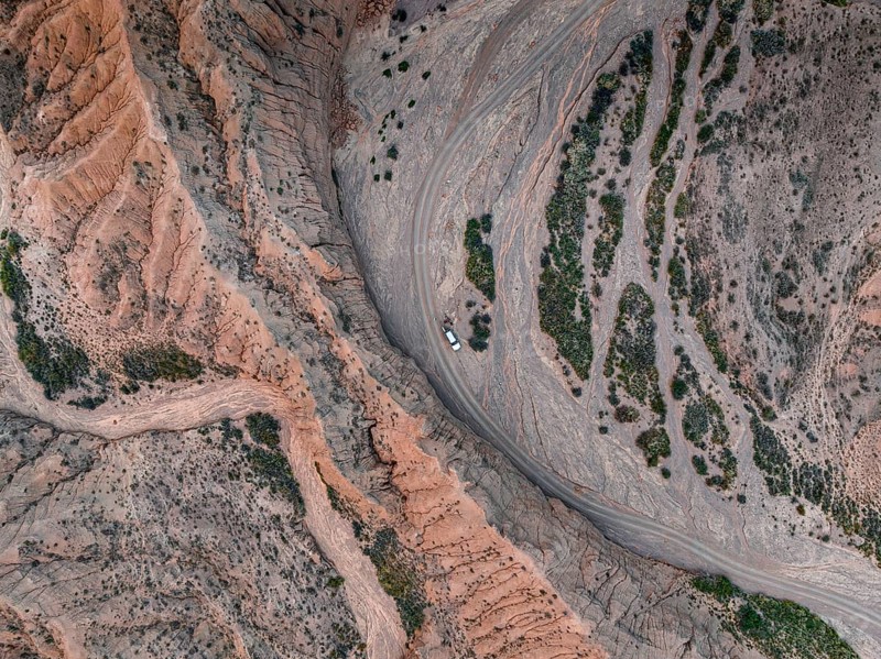 Aerial view, 4x4 car, Camping in dry riverbed, View from above, Canyon runs through landscape, Dramatic barren landscape of eroded hills, Badlands, Canyon of the Forgotten Rivers, Issyk Kul, Kyrgyzstan, Asia