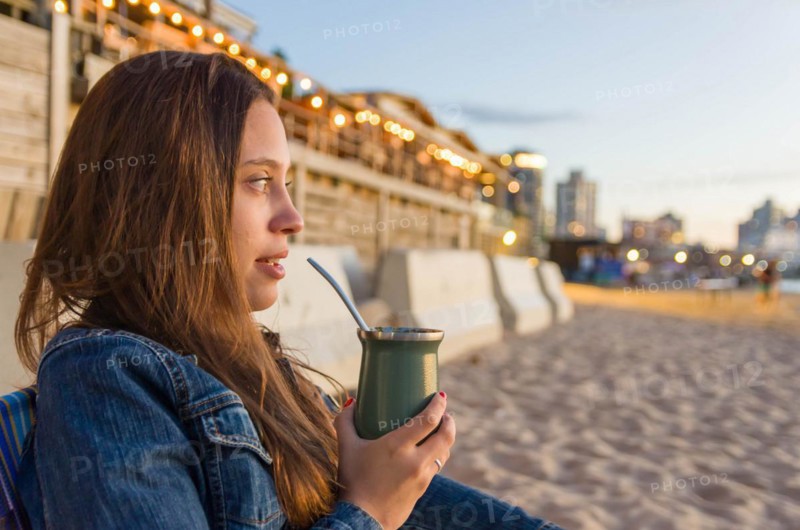 Young girl drinking mate tea tea (chimarrao) on the beach