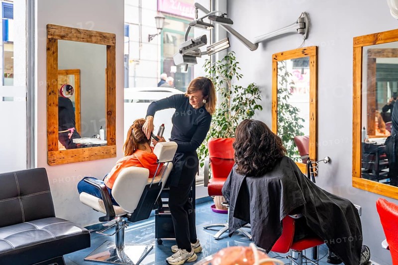 Full length photo of a full beauty salon with hairdresser attending clients
