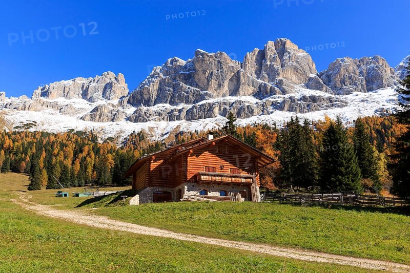 Red roof of a wooden hut in front of a wide mountain panorama under a blue sky, Italy, Alto Adige, Bolzano province, Dolomites, rose garden, Europe