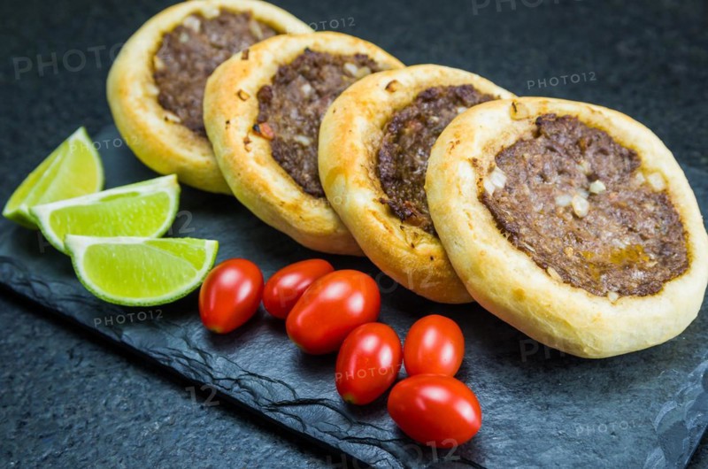 Delicious Lebanese (Arabic) food, genuine sfihas on a slate plate with tomatoes and lemons