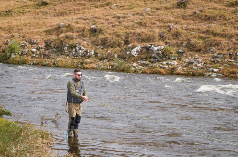 Fisherman fly fishing rainbow trout on mountain in beautiful scenery