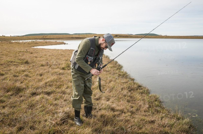 Sport fisherman fishing in lake on cloudy day, Cambara do sul, Rio Grande do sul, Brazil, South America