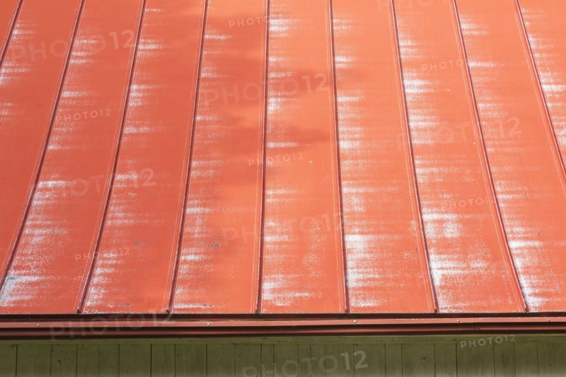 Weathered red standing seam sheet metal roof on old white vertical wood plank and red trim barn, Quebec, Canada, North America