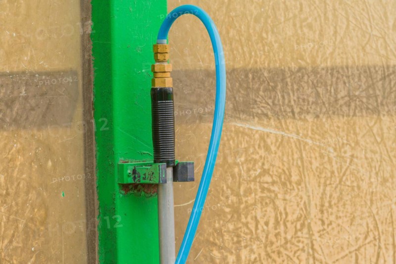 Closeup of handle of car wash brush with attached blue water hose in South Korea