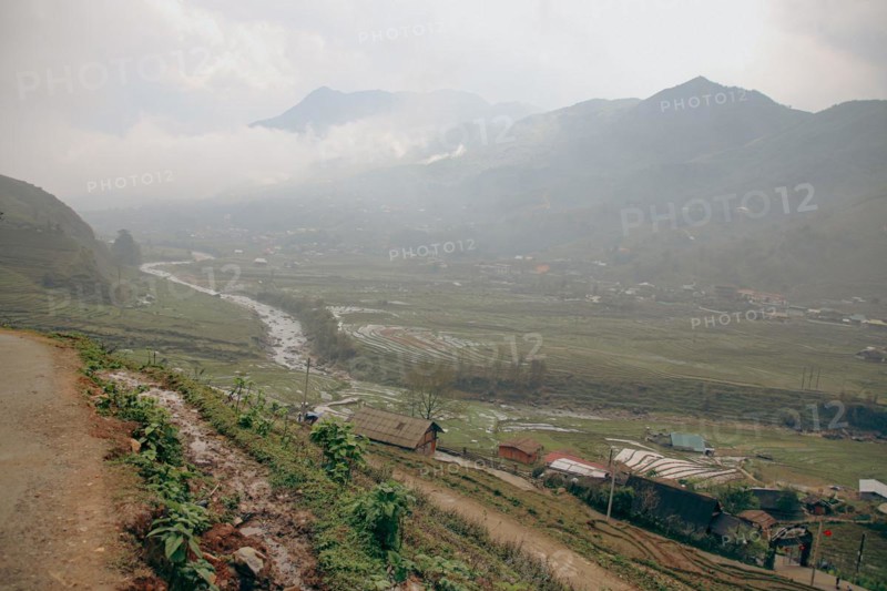 A misty view of a village in a valley with a river flowing through, surrounded by mountains in Lao Cai Village, Sa pa Vietnam