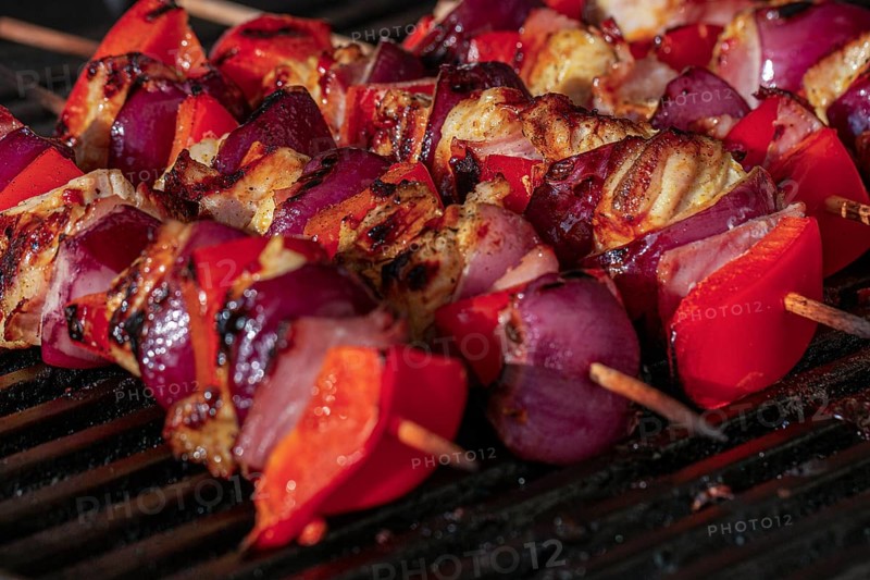 Grilled skewers with Sweet peppers, onions and pieces of chicken on a charcoal grill with visible grill marks