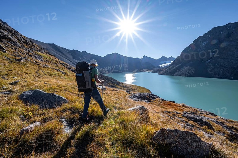 Mountaineers at the turquoise Ala Kul mountain lake in the morning light, Sun Star, Tien Shan Mountains, Kyrgyzstan, Asia
