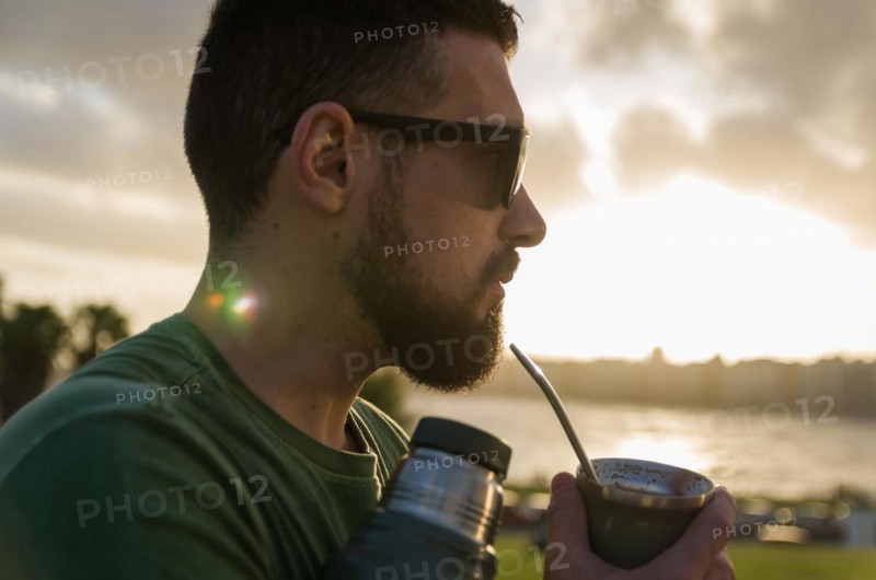 Man drinking chimarrao, mate tea tea (an infusion of yerba mate tea tea with hot water) at sunset in uruguay