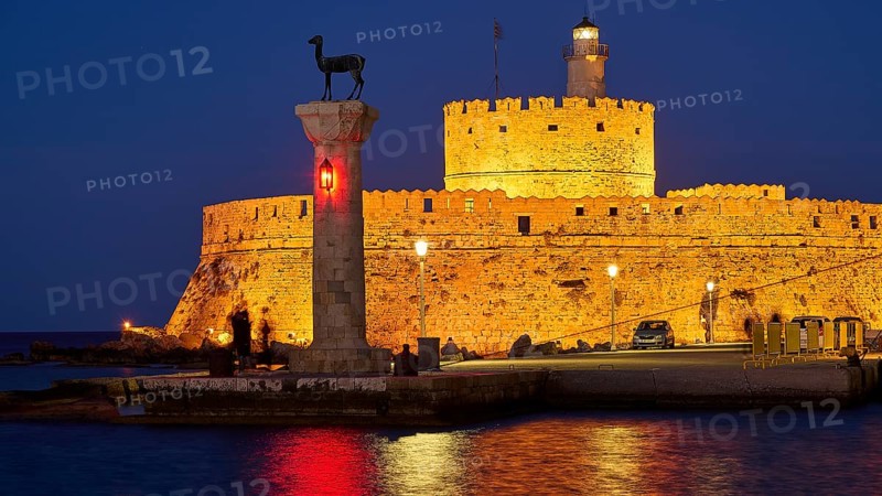 Night view of an old fortress with red lights and a sculpture by the sea, night shot, deer statue, Fort Agios Nikolaos, Mandraki harbour, European roe deer, Rhodes, Dodecanese, Greek Islands, Greece, Europe