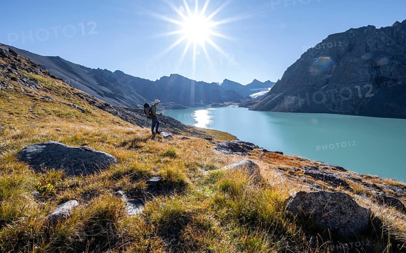 Mountaineers at the turquoise Ala Kul mountain lake in the morning light, Sun Star, Tien Shan Mountains, Kyrgyzstan, Asia