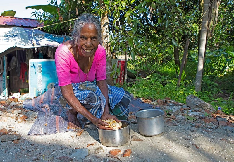 Indian woman, 78 years old, squatting on the floor and washing cassava roots, Kavanattinkara, Backwaters, Kerala, India, Asia