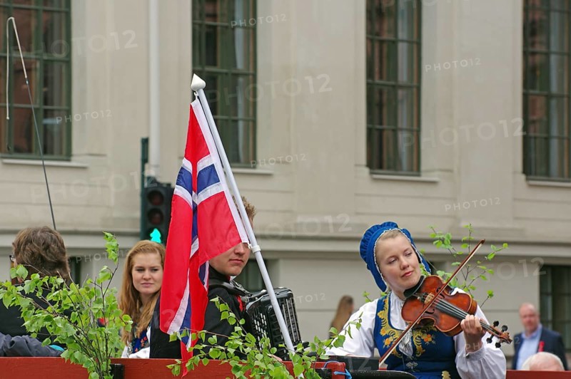 Woman in traditional traditional costume playing in the street, Norwegian national flag next to her, folklore, bank holidays 17 May, Oslo, Norway, Europe