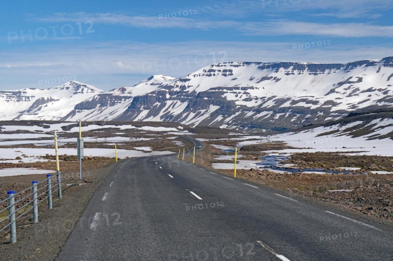Road leads through barren mountain landscape with snow and ice, Seydisfjoerdur, Fjaroarheioi, Iceland, Europe