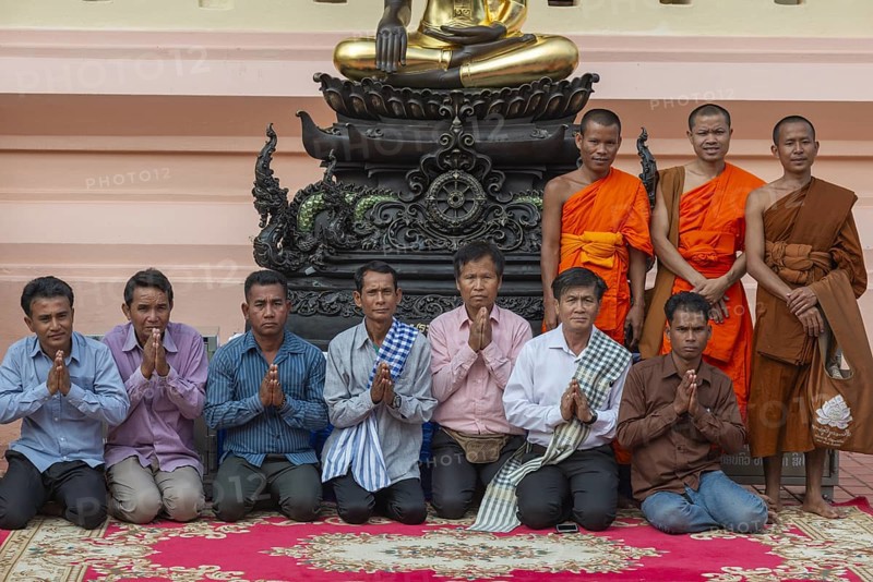 Monks and Laotians in front of a Buddha statue, Bhumispara-mudra, Buddha Gautama at the moment of enlightenment, Wat Ong Teu, Vientiane, Laos, Asia