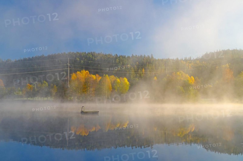 Sunrise and autumn morning mist over a calm lake, bathing island, foliage colouring, Bullaren, Bohuslaen. Sweden