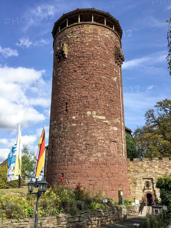 View of large high castle tower of the legendary 13th century fairytale castle Fairytale castle of Rapunzel today Burghotel Trendelburg, artificial braid of Rapunzel attached to the tower side on the right, entrance to castle courtyard on the right, Trendelburg, Weserbergland, Hesse, Germany, Europe