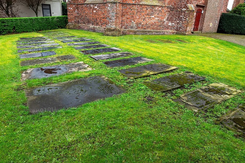 Weathered historical gravestones in the churchyard, Protestant Reformed St George's Church in the small town of Weener, district of Leer, Rheiderland, East Frisia, Lower Saxony, Germany, Europe