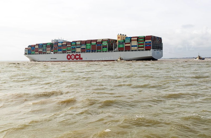 OOCL Zeebrugge container ship leaving departing from Port of Felixstowe, Suffolk, England, UK tugboats at stern