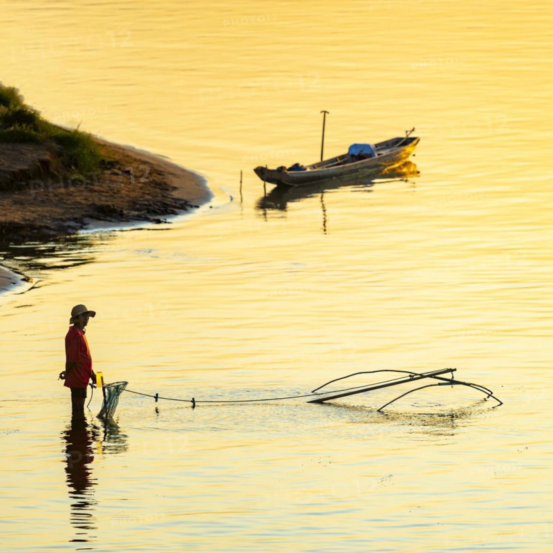 Fisherman with a sinking net at sunset on the Mekong, Luang Prabang, Laos, Asia