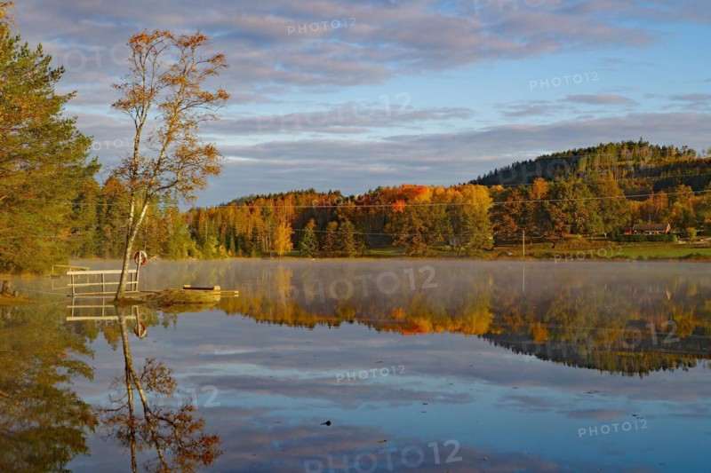 Sunrise and autumnal morning mist over a calm lake, foliage colouring, Bullaren, Bohuslaen. Sweden