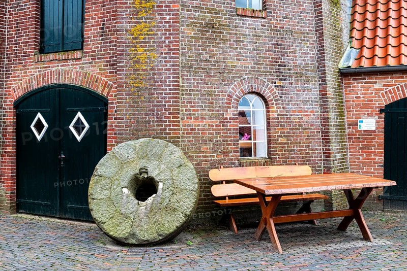 Historic millstone at the old mill in the fishing village of Ditzum, municipality of Jemgum, district of Leer, Rheiderland, East Frisia, Lower Saxony, Germany, Europe