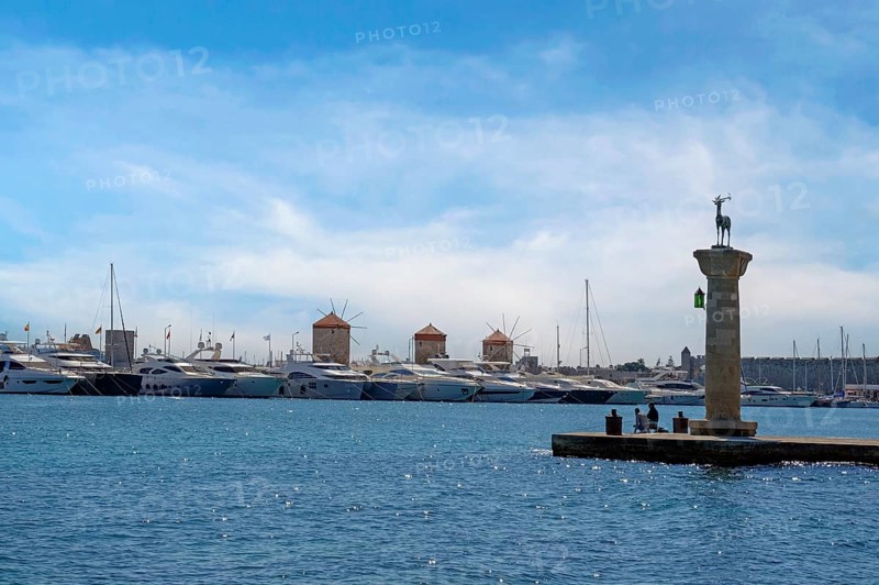 Deer Elafos, sculpture on a column, at the entrance to the harbour, in the background the three windmills of Rhodes, Mandraki harbour, Rhodes, Rhodes island, Dodecanese, Greece, Europe