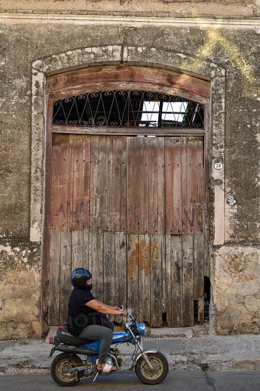 Fat woman on a moped in front of an old warehouse, rural scene in Victoria, Duck, Argentina, South America