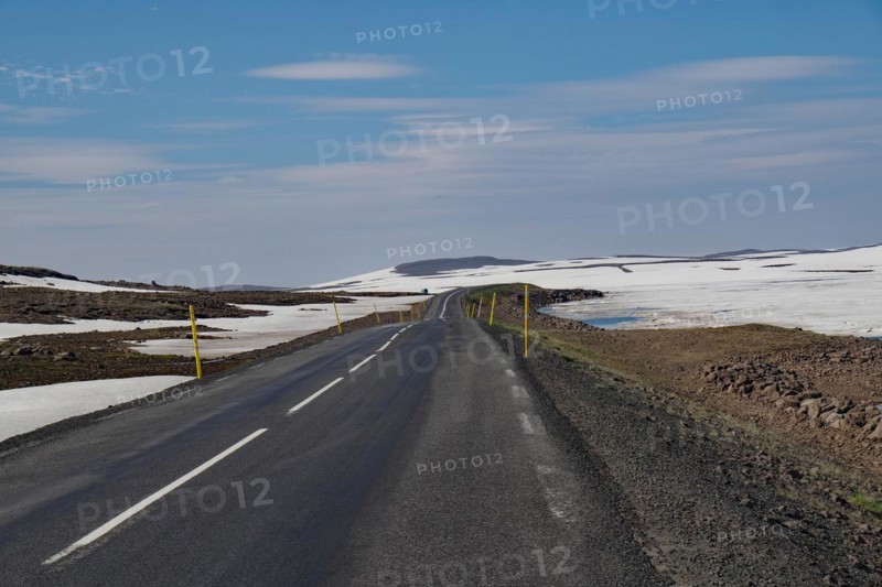 Road leads through barren mountain landscape with snow and ice, Seydisfjoerdur, Fjaroarheioi, Iceland, Europe